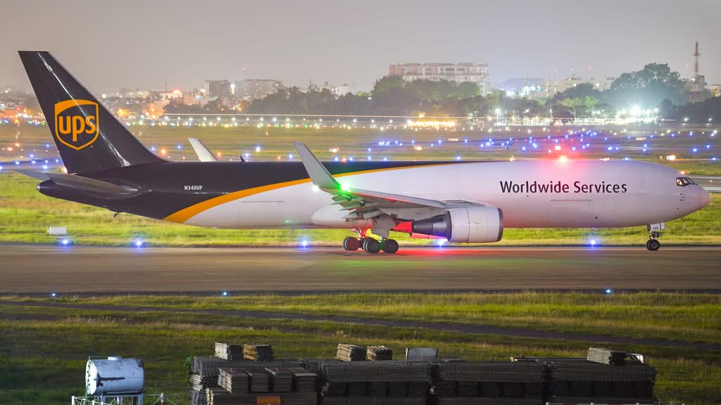 A UPS cargo plane on a lit runway at night showcasing logistics and transportation.