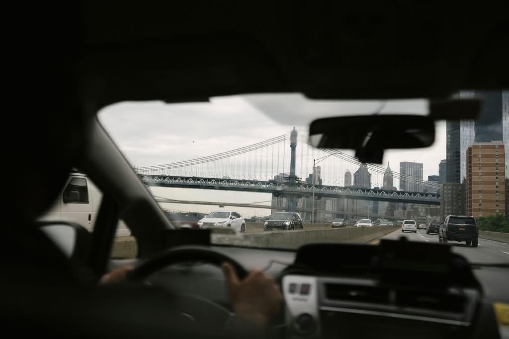 How To Book A Taxi Ride From JFK To Manhattan: 2026 Honest Guide 7 Back view of anonymous male driving car along roadway against bridge on urban background in soft daylight
